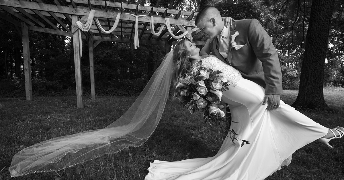 A veil spans the width of a photo as a couple performs a stunning dip.